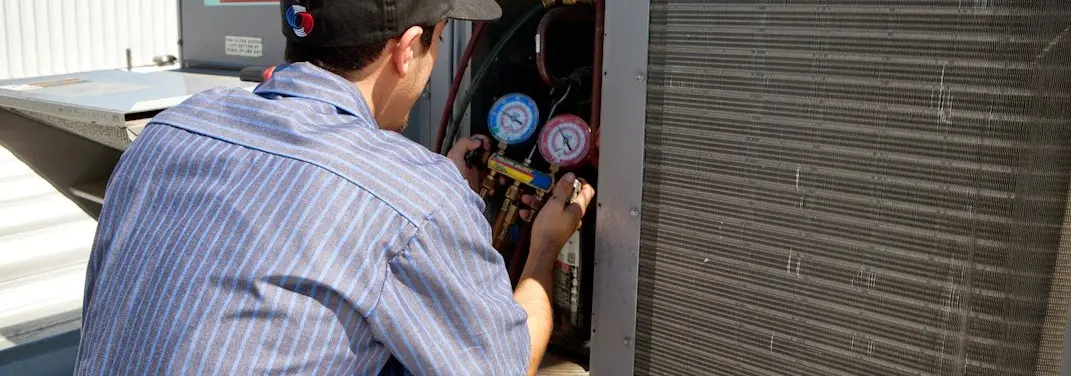 HVAC technician servicing a condenser unit in Catoosa